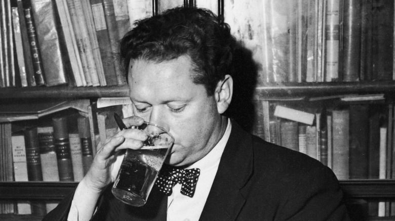 Poet Dylan Thomas drinking a beer while holding a pen