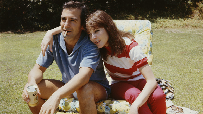Actor Ben Gazzara smoking a cigarette and holding a can of beer, sitting next to his wife, in the 1960s