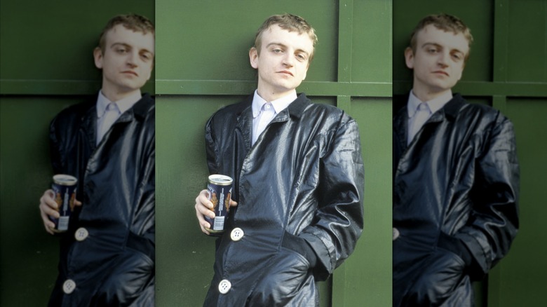 A singer from 1985 holding a can of beer outside