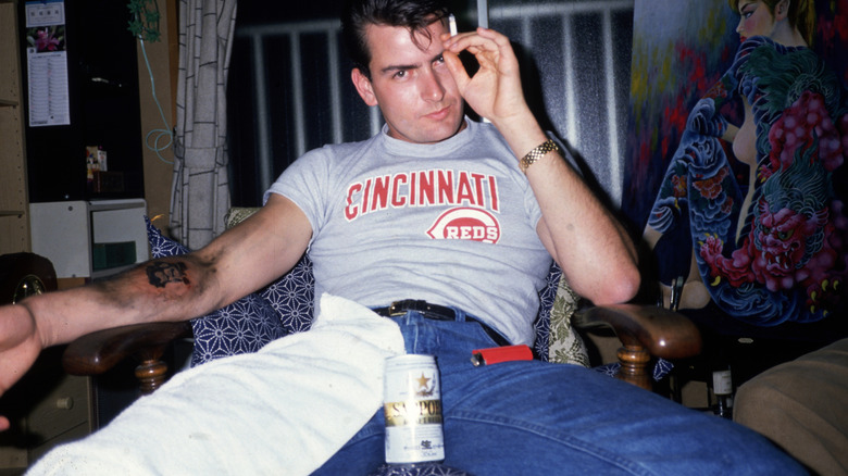 Charlie Sheen sitting with a cigarette and a beer, around 1990