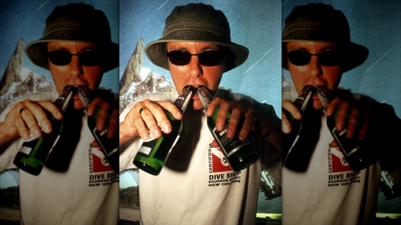 Novelist Irvine Welsh holding bottles of beer, mirrored