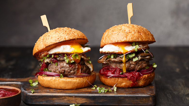 Two homemade beef burgers with egg and red onion