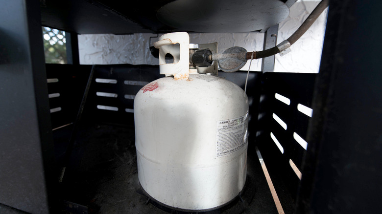 A propane gas tank under a barbecue grill
