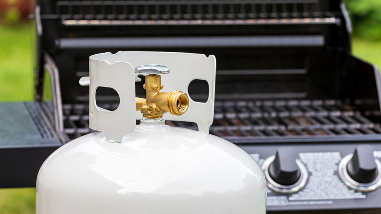 A new propane gas tank next to a barbecue grill