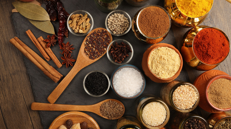 Overhead view of various small bowls and spoons, each holding a different type of spice