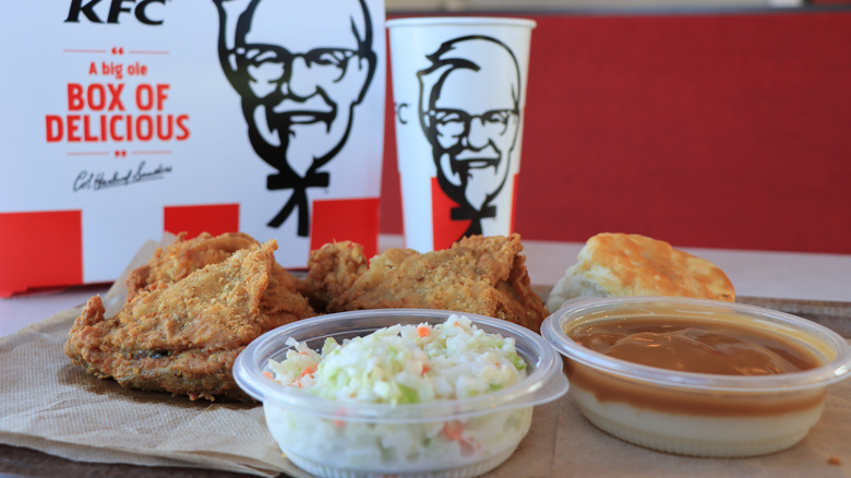 A KFC boxed meal consisting of two pieces of chicken, a biscuit, coleslaw, and mashed potatoes with gravy