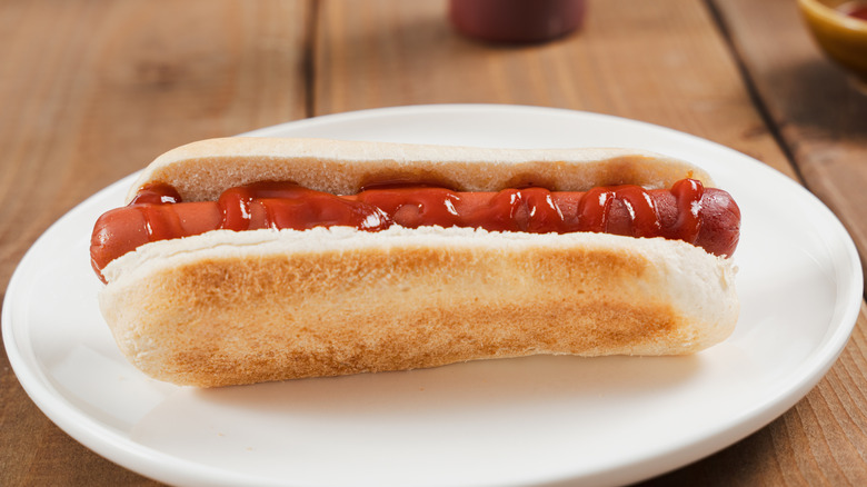 Hot dog with ketchup on white plate