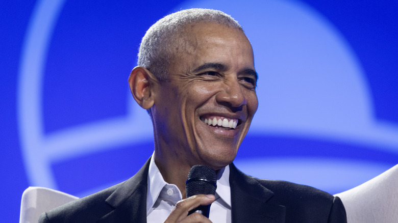 Barack Obama smiling and holding a microphone