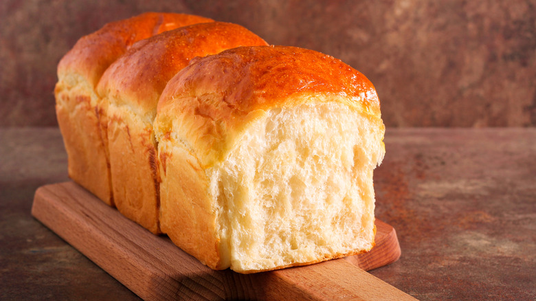 Soft, fluffy loaf of Japanese milk bread on wooden board