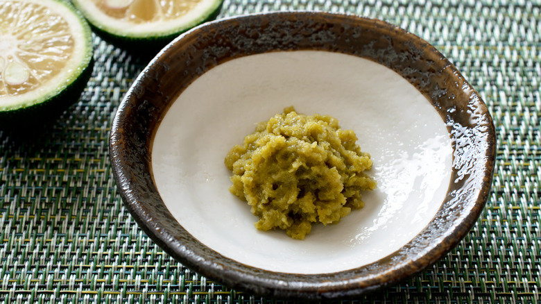 A bowl of Japanese yuzu kosho citrus chili paste with fresh yuzu halves