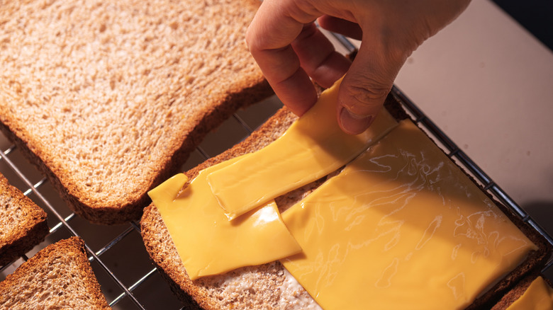 hand putting cheese on oven bread