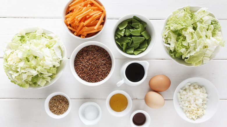 Multiple bowls of raw ingredients on white wood