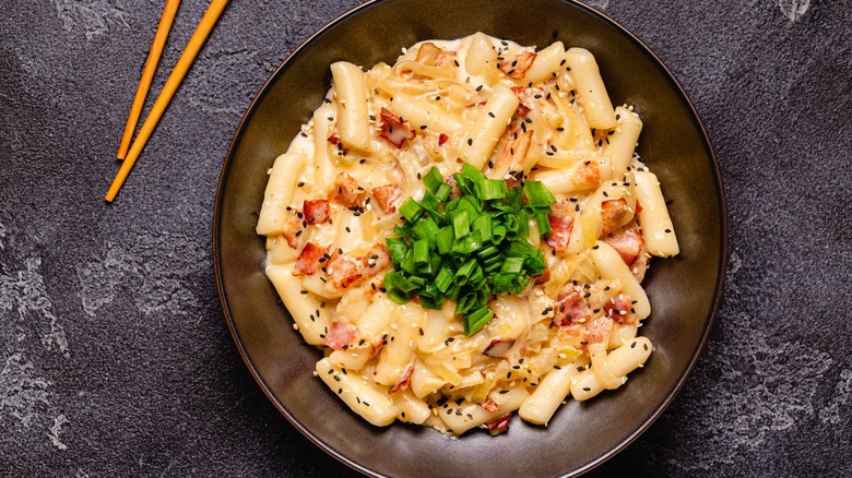 Tteok and cheese in a black bowl.