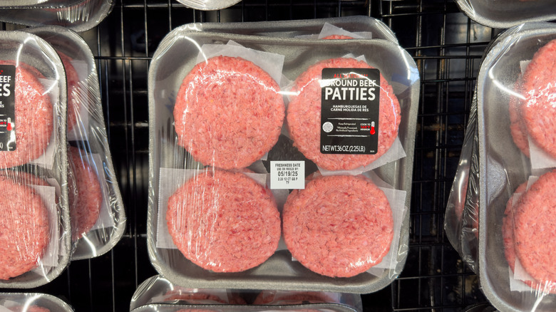 Packaged ground beef patties on grocery store shelf.