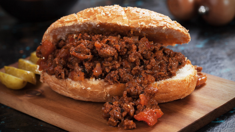 A sloppy joe sandwich on a wooden cutting board