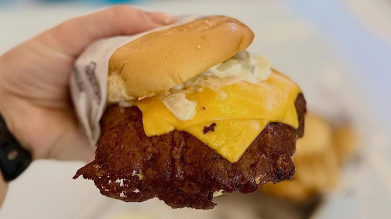 Hand holding a Signature Cowy Burger from Miami