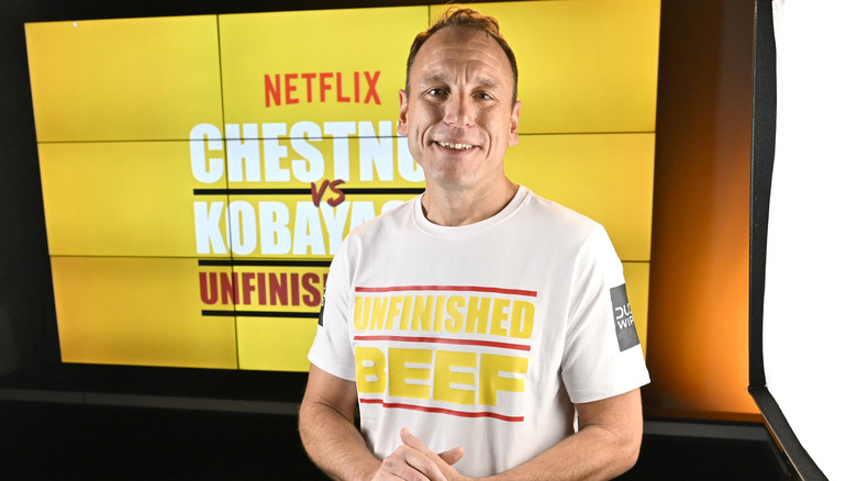 Joey Chestnut with sign and shirt promoting "Unfinished Beef"