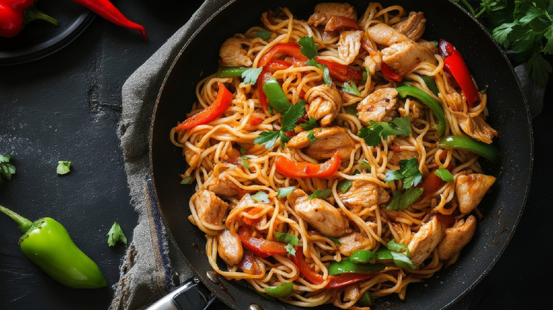 Chicken noodle stir fry in a black pan
