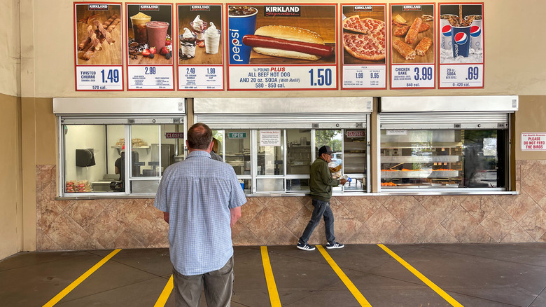 Two patrons stand near the exterior of a Costco food court