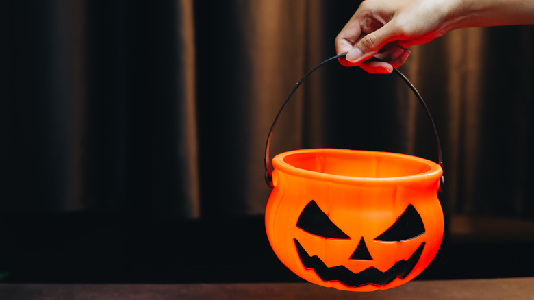 Hand holding an empty trick or treat bucket