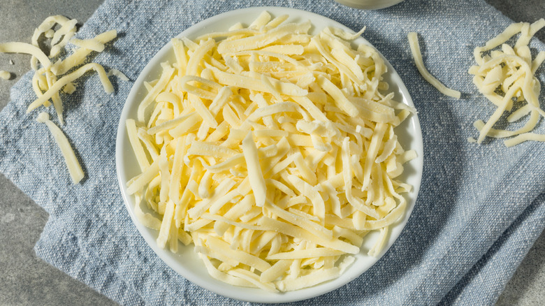Top view of shredded mozzarella cheese in white bowl
