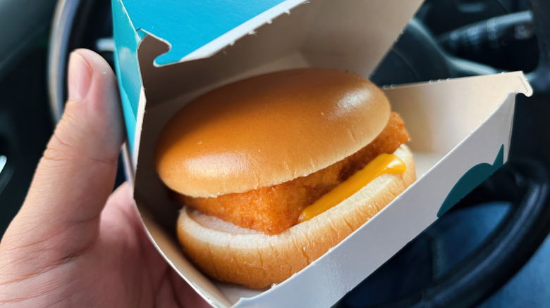 hand holding a Filet-O-Fish sandwich in a McDonald's cardboard carton