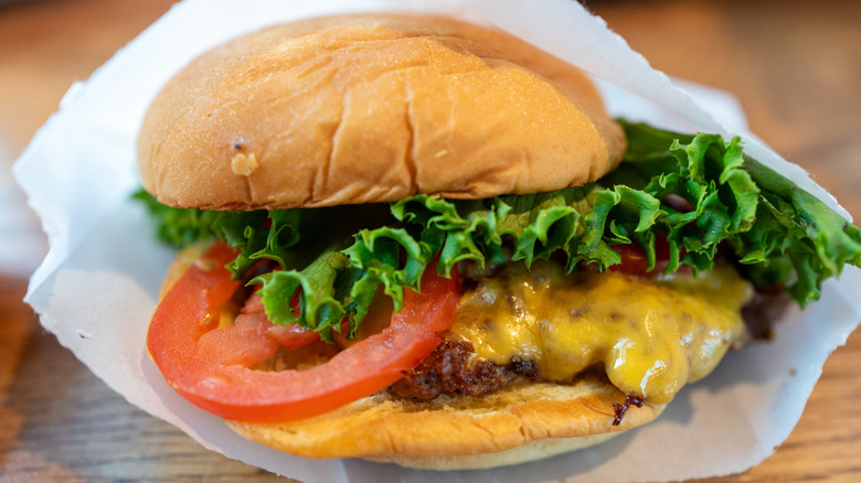 Close-up of a Shake Shack cheeseburger with lettuce and tomato