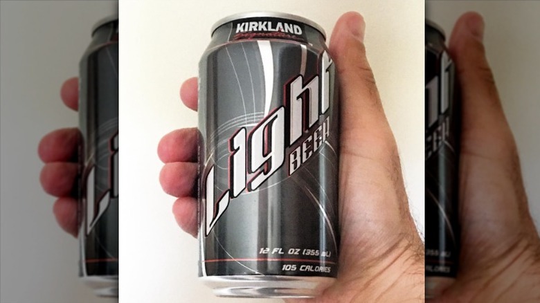 A hand holding a can of Kirkland Signature Light beer