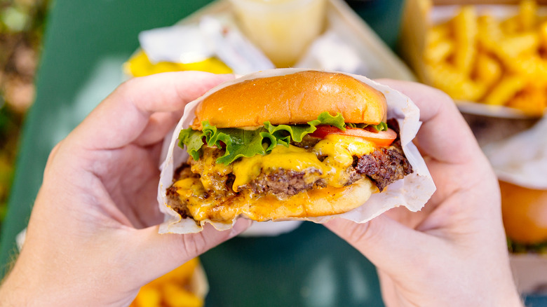 Hands holding fast food burger