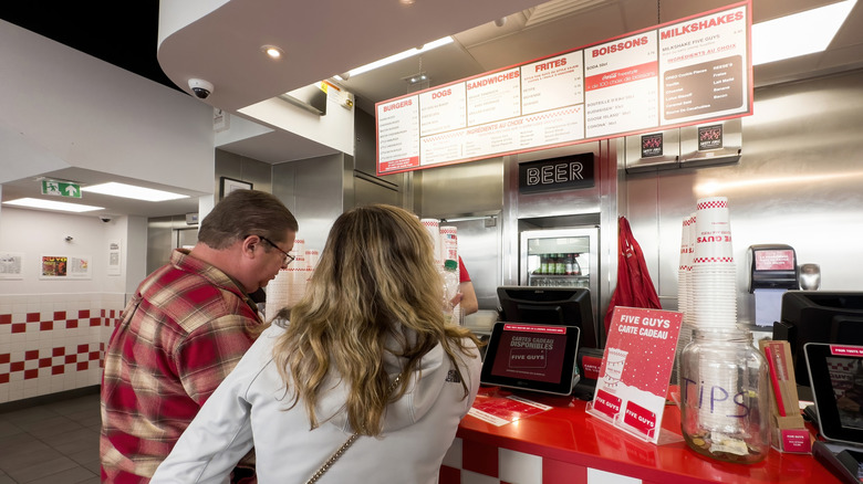 A couple orders food at a Five Guys restaurant