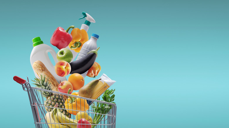 A shopping cart with various grocery items magically erupting out of the top over a teal background.