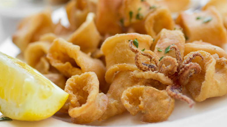 Italian-style fried calamari with a wedge of lemon on a plate