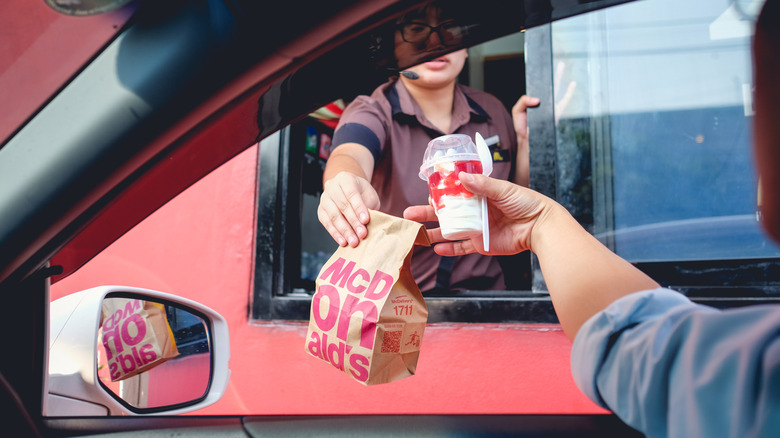 Person handing over McDonald's order in drive-thru.