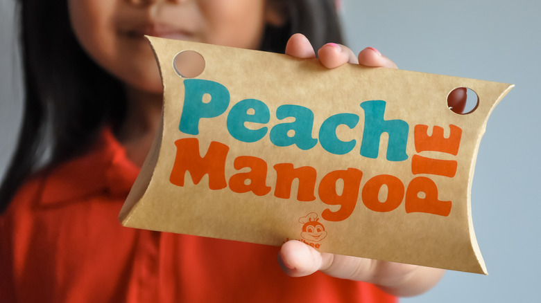 Child holding up peach mango pie package from Jollibee.