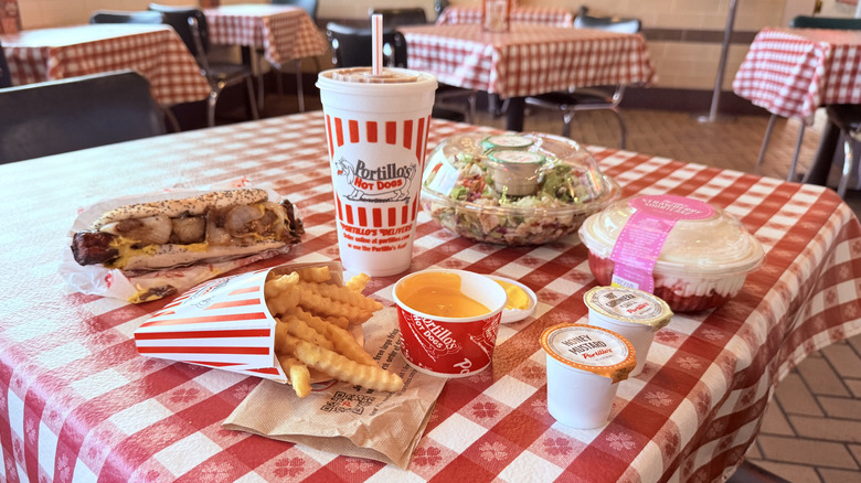 Full spread of Portillo's food on table with red checkered plastic tablecloth.