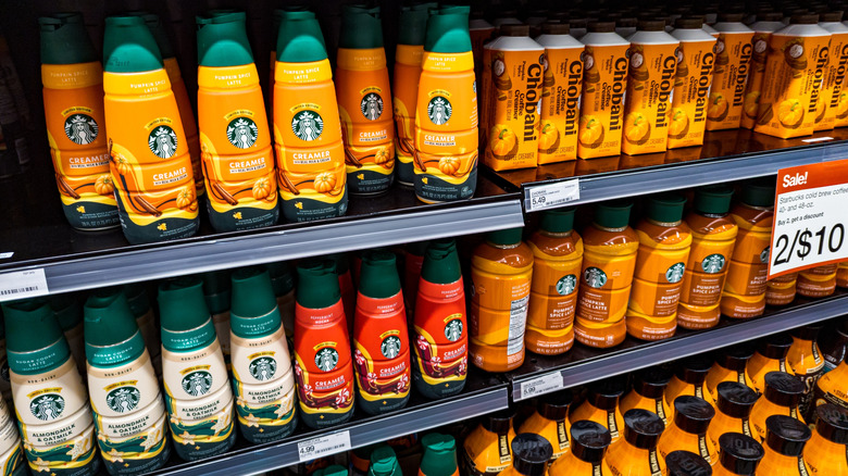 A variety of pumpkin spice creamers on a supermarket shelf.