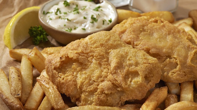 A platter of fried fish with fries, lemon, and tartar sauce.