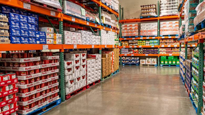 An empty Costco aisle with canned tomatoes, mayonnaise, and other products.