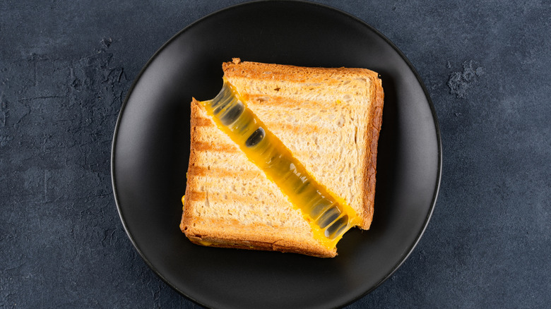 A grilled cheese sandwich cut into two triangles sitting on a black plate