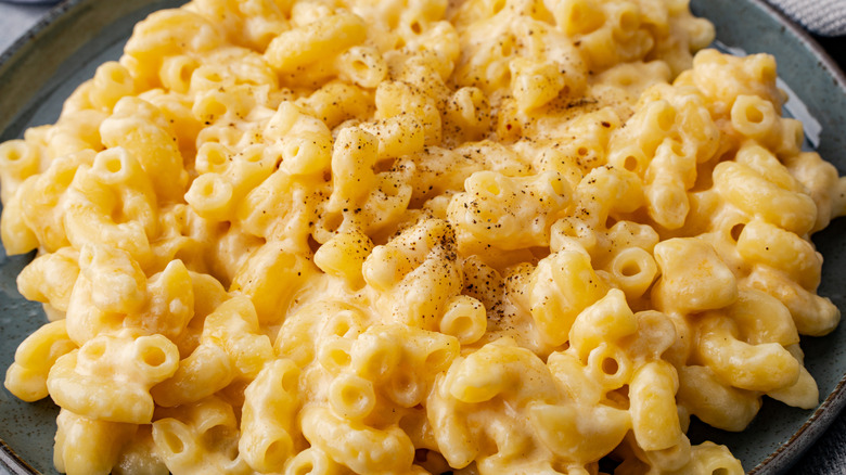 A close-up of mac and cheese with black pepper on a gray plate