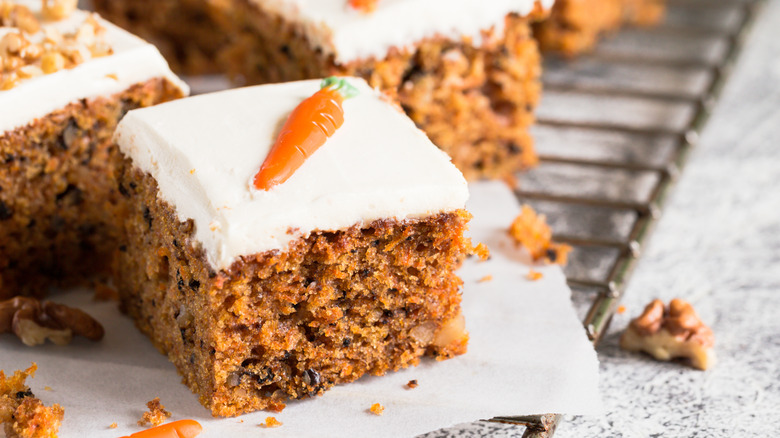 Square of carrot cake with cream cheese frosting and orange carrot decoration