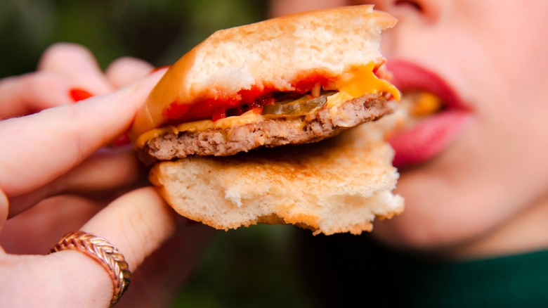 Close up of woman eating cheeseburger outdoors in street