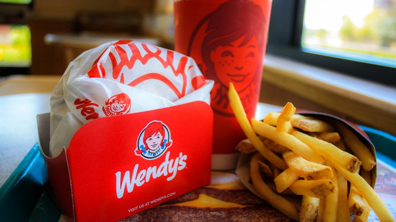 Wendy's burger, fries, and drink on tray in restaurant