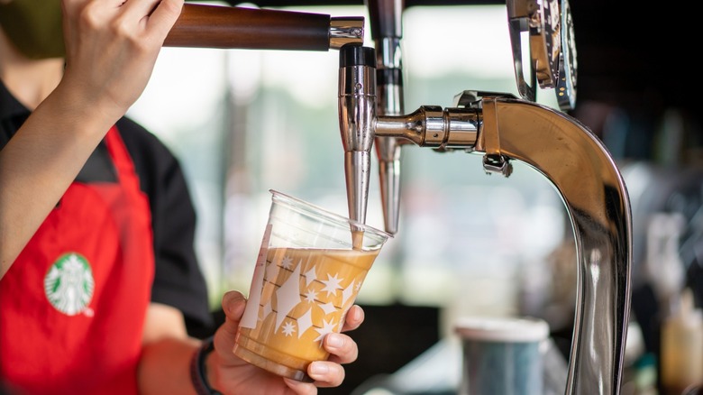 Starbucks employee pouring a cup of nitro cold brew