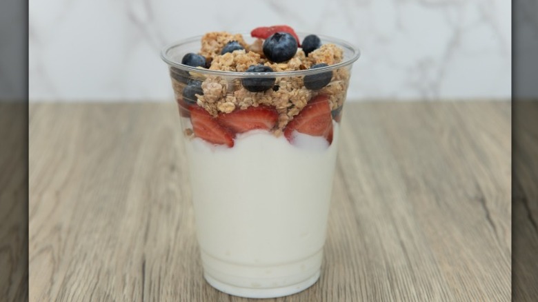 A fruit and granola yogurt parfait in a plastic cup