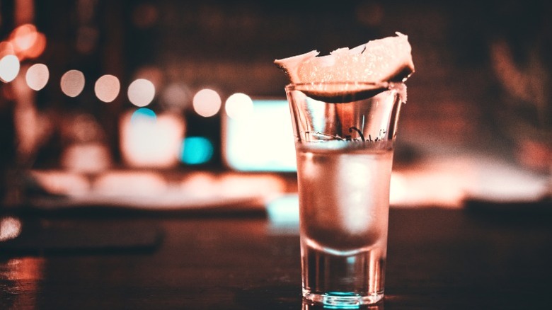A shot of tequila with a lime wedge.