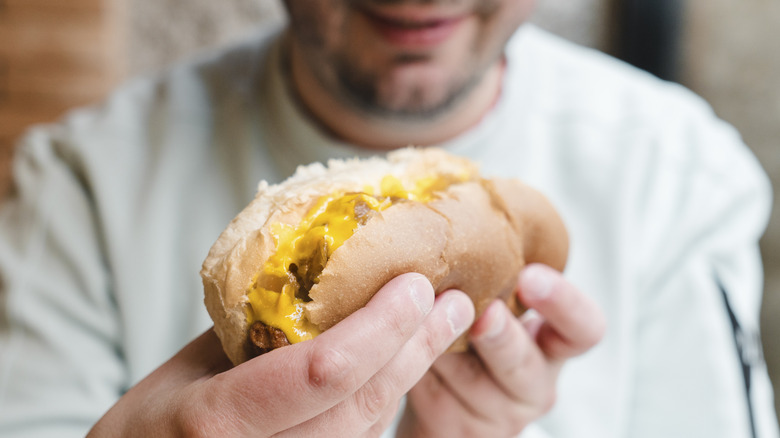A man about to eat a smothered hot dog