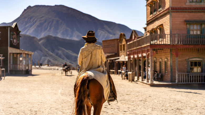 A cowboy rides his horse into an Old West town