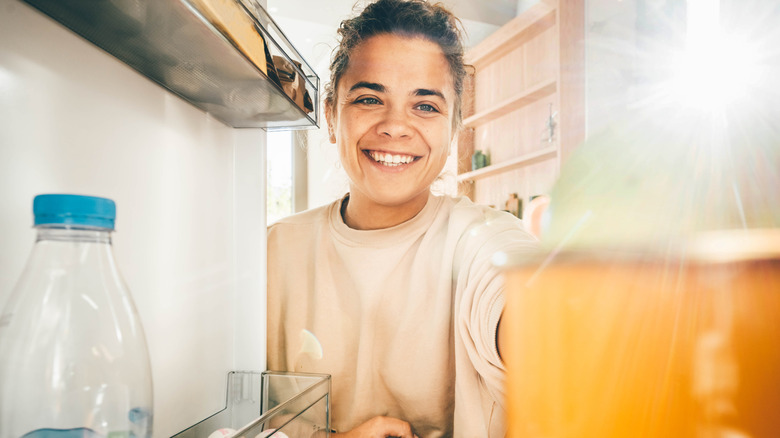 Woman opening fridge and grabbing food