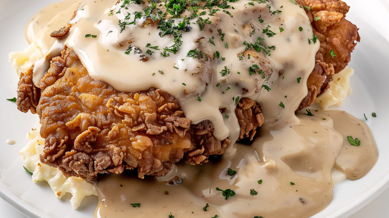 Closeup with country fried steak smothered in gravy.